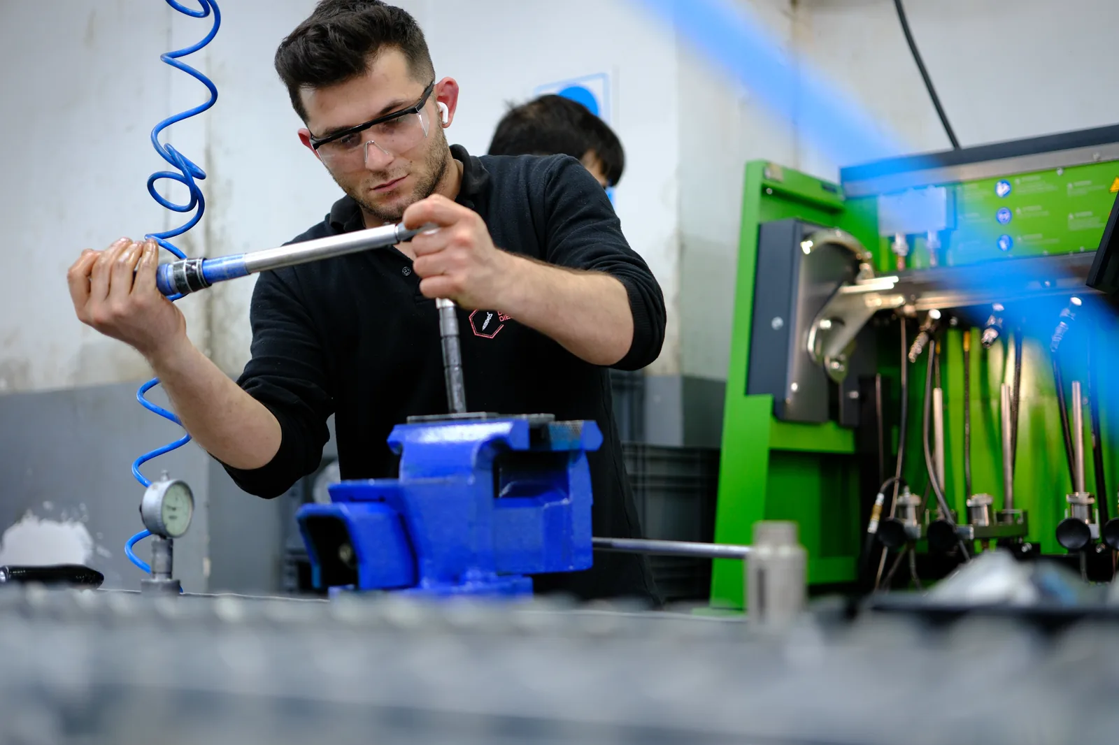 Dizel test ekipmanının yanında enjektör bileşenini inceleyen teknisyen