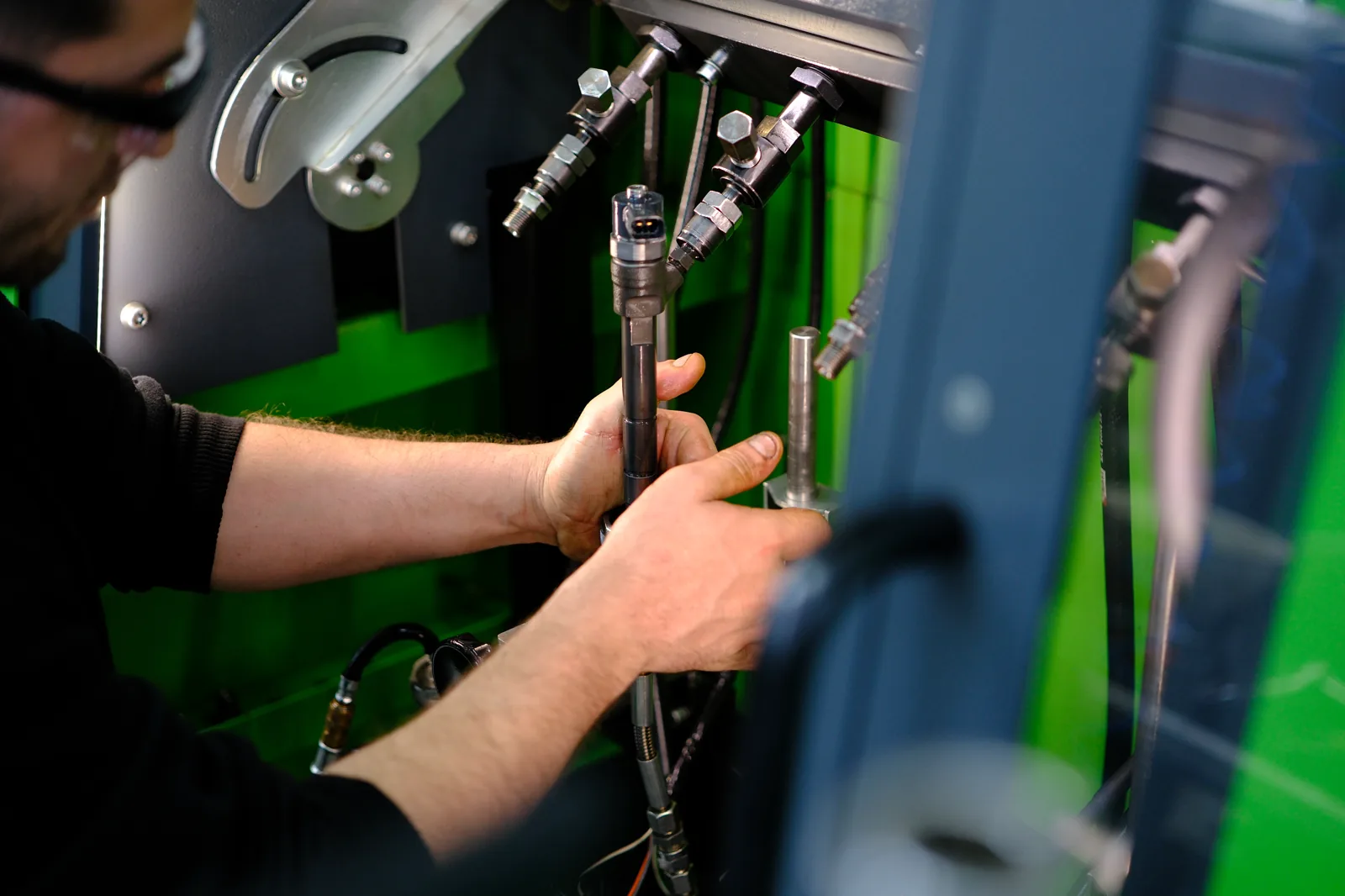 Technician connecting a diesel injector to dedicated test equipment